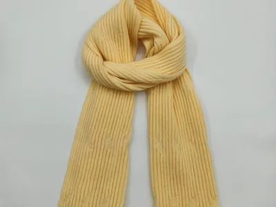 Zart gelber Schal aus feinem Rippenstrickgewebe, flach gelegt auf weißem Hintergrund, vertikale Strickstruktur erkennbar