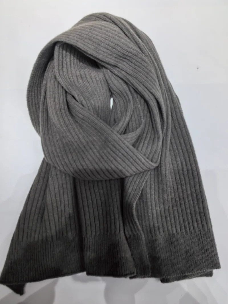 Graumelierter Rippenstrickschal locker aufgerollt vor weißem Hintergrund mit sichtbarer weicher Stricktextur