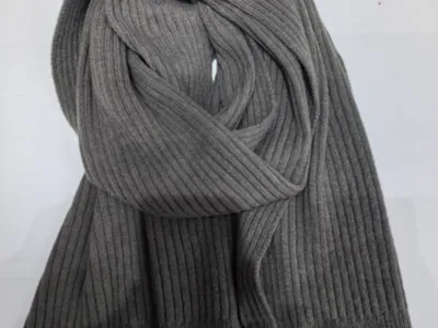 Graumelierter Rippenstrickschal locker aufgerollt vor weißem Hintergrund mit sichtbarer weicher Stricktextur