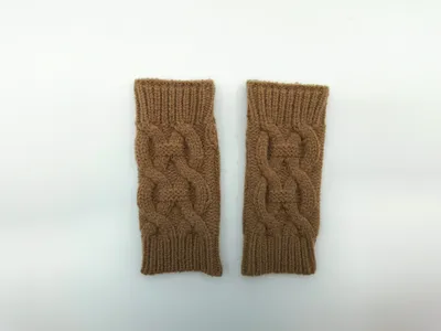 Fingerlose Strickhandschuhe in warmen Kamelbraun-Tönen mit geflochtenem Reliefmuster, flach auf hellem Untergrund fotografiert