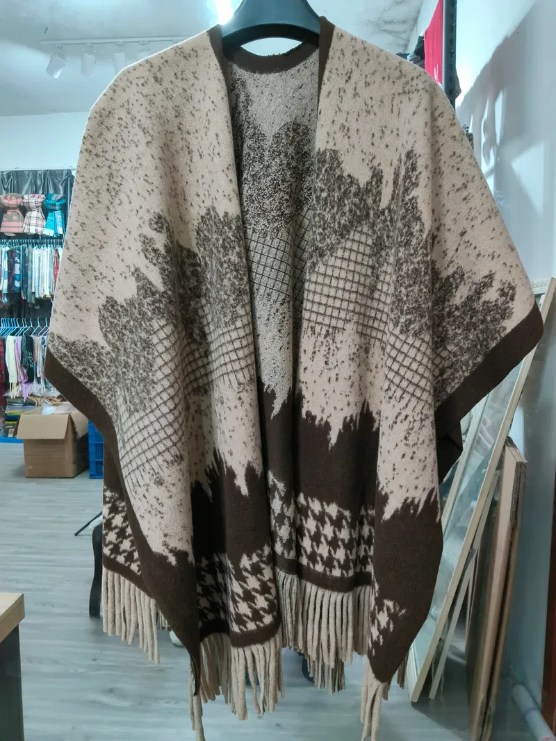 Großer Strickponcho in Beige und Braun mit Blattmotiv-Jacquard, Hahnentritt-Bordüre und Fransensaum auf einem Kleiderbügel