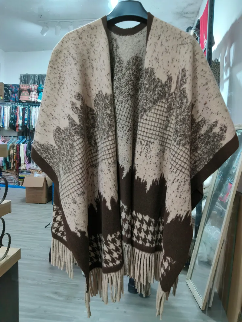 Offener Strickponcho in Beige und Braun mit floralem Jacquardmuster, Hahnentritt-Bordüre und Fransenabschluss auf Bügel