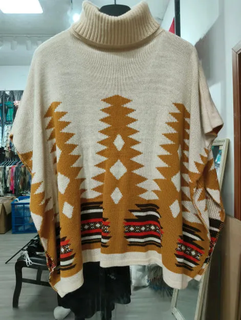 Oversize-Strickponcho in Creme mit Rollkragen und geometrischem Aztekenmuster in Senfgelb und Rot auf Kleiderbügel