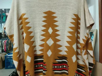 Oversize-Strickponcho in Creme mit Rollkragen und geometrischem Aztekenmuster in Senfgelb und Rot auf Kleiderbügel