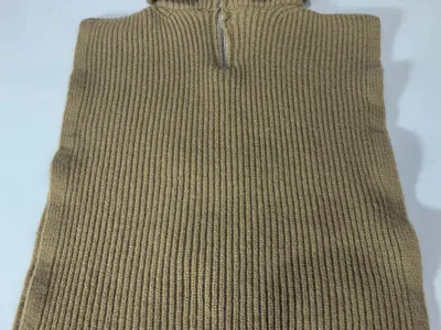 Ärmellose Strickponcho-Weste in warmem Kamelorange mit silberfarbenem Halbzipper am Stehkragen, flach auf weißem Untergrund