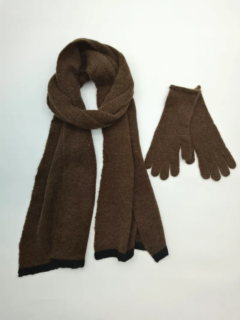 Braunes Strick-Schal und passendes Handschuh-Set mit schwarzem Kontrastrand auf weißem Hintergrund