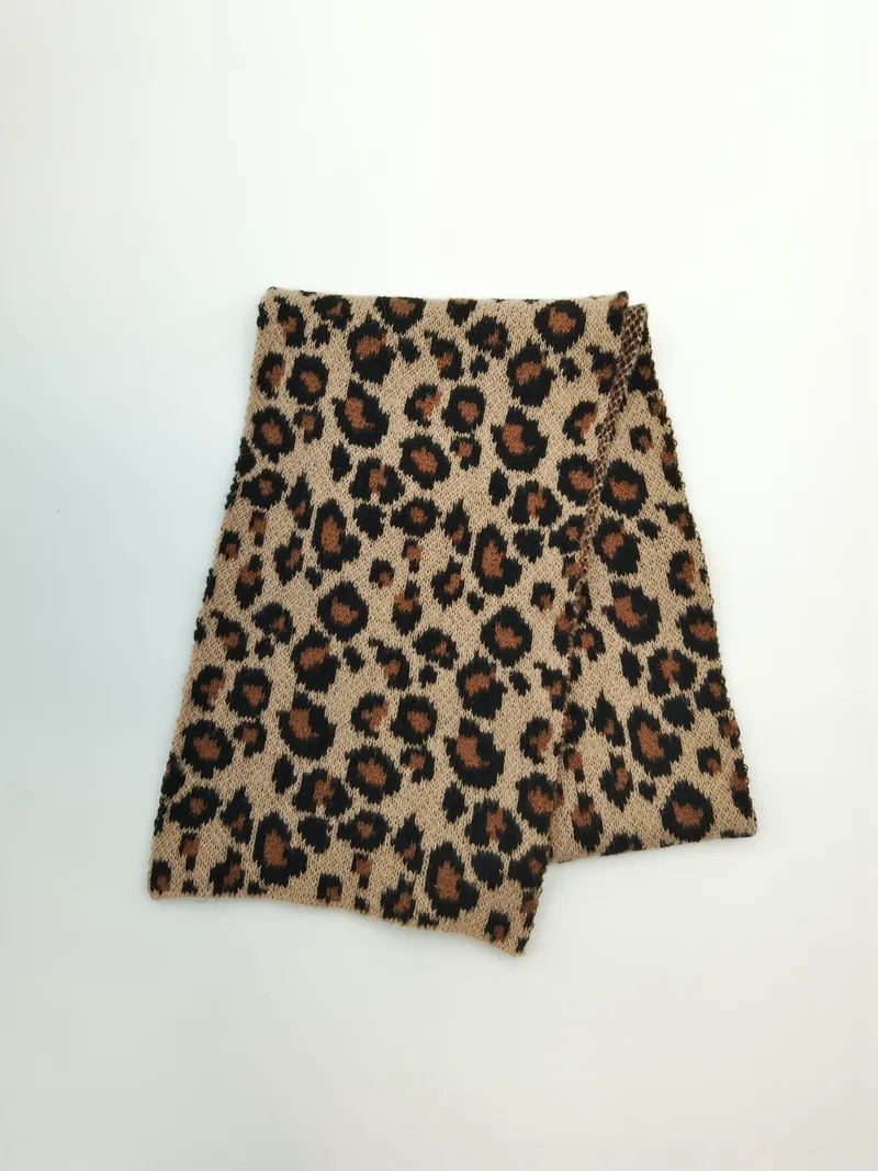 Zusammengefalteter Strickschlauchschal mit Leopardenmuster in Creme und Karamell auf weißem Hintergrund