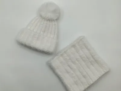 Weißes weiches Rippenstrick-Winterset mit Pompon-Mütze und passenden Halsschlauch-Snood auf weißem Untergrund