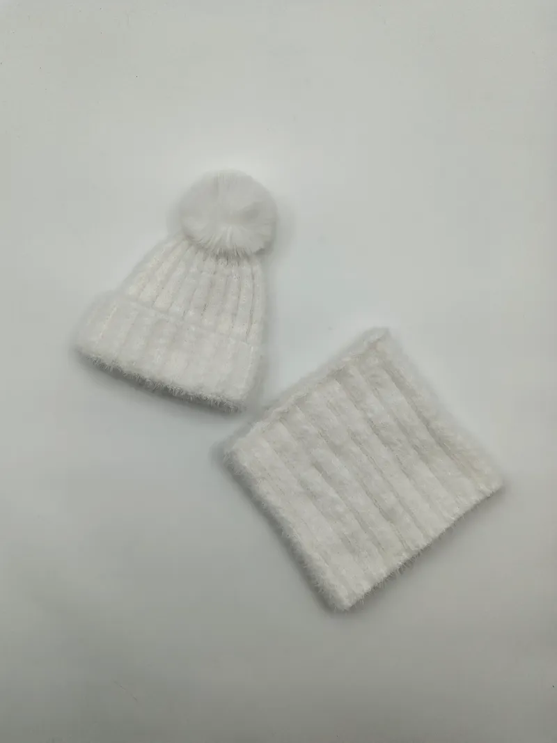 Weißes weiches Rippenstrick-Winterset mit Pompon-Mütze und passenden Halsschlauch-Snood auf weißem Untergrund