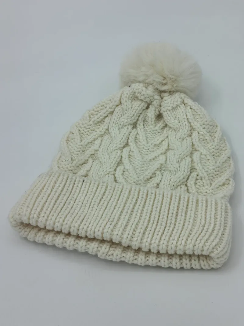 Wintermütze in Cremeweiss mit großem flauschigem Bommel, grobem Zopfstrickmuster und doppelt umgeschlagenem Rippenbündchen