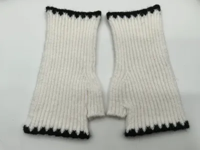 Paar weiße Rippenstrick-Fingerhandschuhe mit schwarz-weißem Zickzack-Abschlussband oben und unten, flach auf weißem Hintergrund