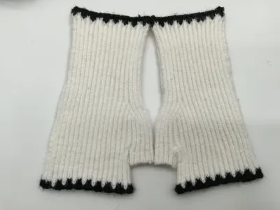 Draufsicht auf handgestrickte weiße Rippenstrick-Fingerhandschuhe mit schwarzen Kontrastbündchen an Handgelenk und Fingeröffnungen