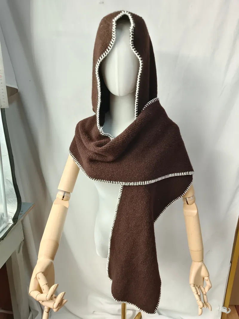 Dunkelbrauner gestrickter Kapuzenscarf-Umhang mit weißer Blanket-Stitch-Bordüre auf Schneiderpuppe mit Holzarmen