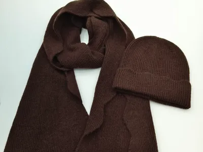 Schokoladenbrauner Rippenstrick-Schal mit Bogensaum und passende Beanie-Mütze auf weißem Untergrund