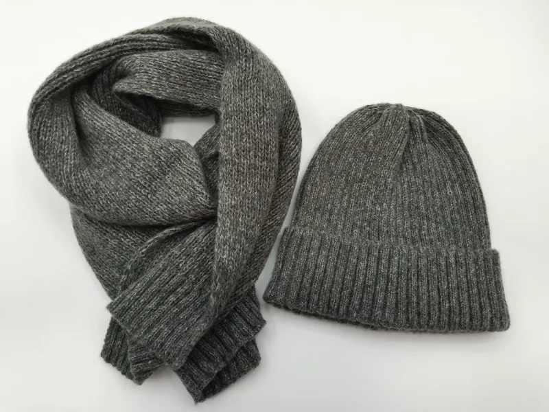 Grau melierter Rippenstrick-Beanie und passender langer Strickschal, flach auf weißem Hintergrund ausgelegt