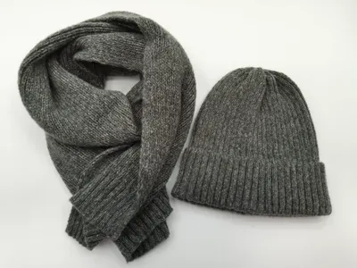 Grau melierter Rippenstrick-Beanie und passender langer Strickschal, flach auf weißem Hintergrund ausgelegt