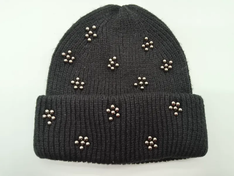 Schwarze Umschlag-Beanie aus Rippenstrick mit dekorativen silbernen Metallperlen in Blütenform auf der Krempe