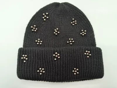 Schwarze Umschlag-Beanie aus Rippenstrick mit dekorativen silbernen Metallperlen in Blütenform auf der Krempe