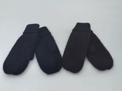 Zwei Paar klobige Strickfäustlinge in Schwarz und tiefem Dunkelbraun nebeneinander auf weißem Untergrund mit sichtbaren Rippbündchen und flauschiger Oberfläche