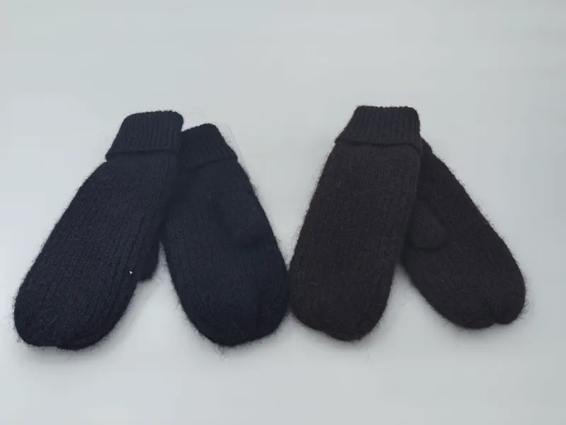 Zwei Paar klobige Strickfäustlinge in Schwarz und tiefem Dunkelbraun nebeneinander auf weißem Untergrund mit sichtbaren Rippbündchen und flauschiger Oberfläche