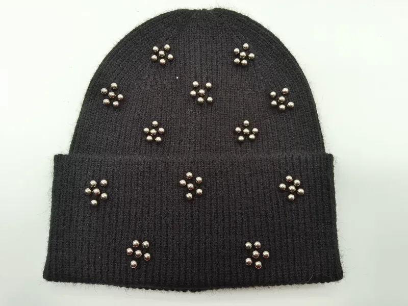 Schwarze Strick-Beanie mit Metallkugelnieten in floralen Cluster-Anordnungen auf Krempe und Kappe