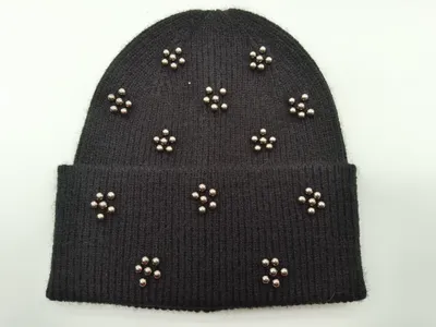 Schwarze Strick-Beanie mit Metallkugelnieten in floralen Cluster-Anordnungen auf Krempe und Kappe