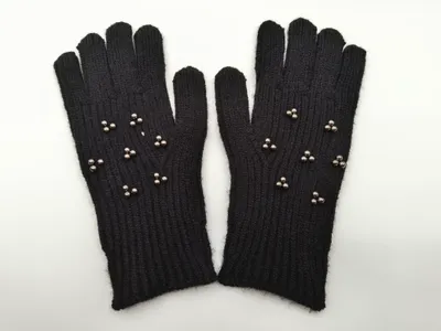Paar schwarze gestrickte Winterhandschuhe mit silbernen Metallniet-Verzierungen auf dem Handrücken