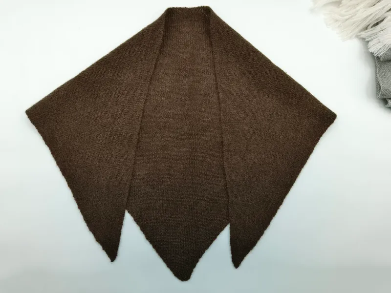 Dunkelbraunes handgestricktes Dreieck-Schultertuch mit drei Zacken, flach auf weißem Untergrund ausgelegt