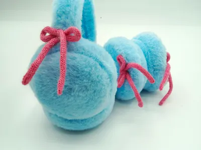 Weiche Ohrenschützer in Babyblau aus Kunstfell mit gestrickter rosa Schleifendekoration – Detailaufnahme auf hellem Untergrund