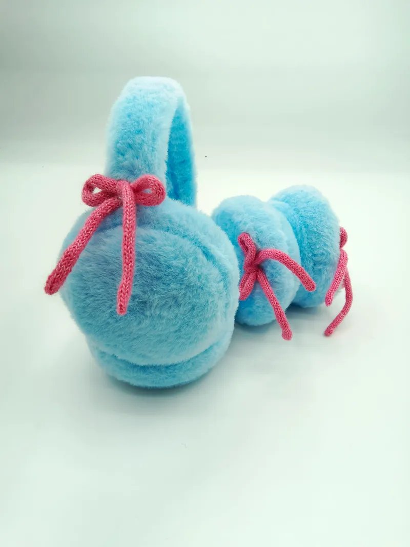 Weiche Ohrenschützer in Babyblau aus Kunstfell mit gestrickter rosa Schleifendekoration – Detailaufnahme auf hellem Untergrund