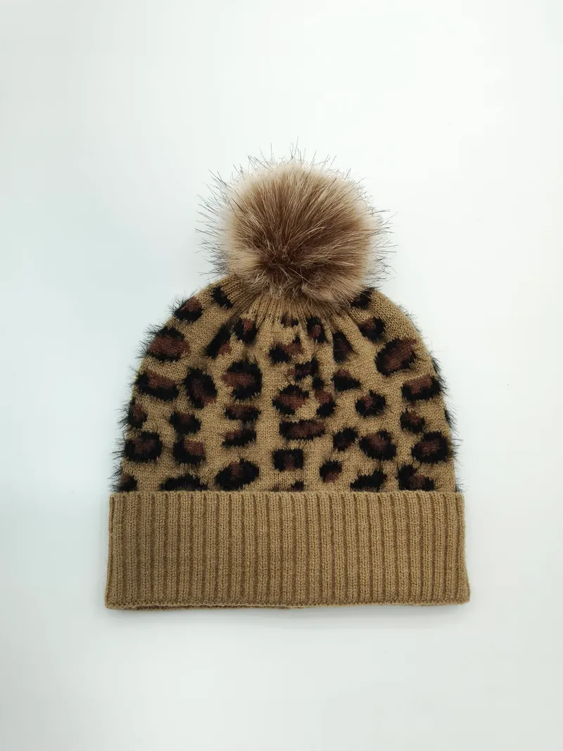 Kamelbraune gestrickte Beanie im Leopardenprint mit fluffigem Kunstpelz-Bommel auf der Spitze – Draufsicht auf weißem Hintergrund