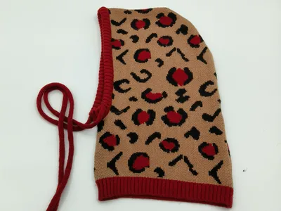 Beige-rote gestrickte Sturmhaube mit Leopardenmuster, rotem Rippensaum und Schnürbändern zum Binden – Flachansicht auf weißem Hintergrund
