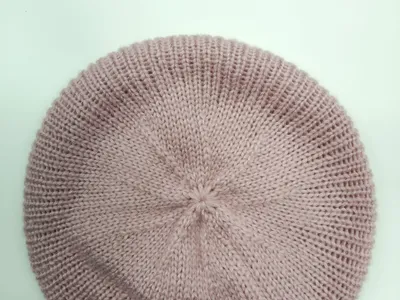 Draufsicht auf eine altrosa Rippenstrick-Baskenmütze mit spiralförmiger Kronennaht, flach auf weißem Untergrund liegend