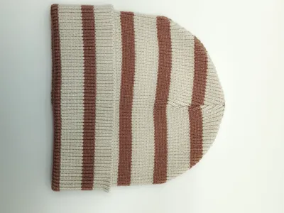 Flach aufgelegte Rippenstrickmütze mit abwechselnden Streifen in Creme und Sandbraun, umgeklapptes Bündchen auf weißem Hintergrund