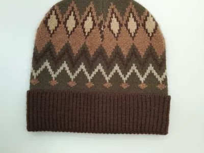 Gestrickte Wintermütze im traditionellen Fair-Isle-Stil mit Rauten- und Zickzackmuster in Erdbraun, Olivgrün und Naturweiß – mit breitem Rippenbündchen