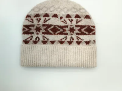 Wintermütze in Creme mit geometrischem Schneeflocken-Jacquardmuster in Terrakotta und umgeschlagenem Bündchen, Draufsicht auf hellem Untergrund