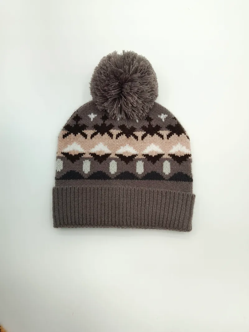 Grau gestrickte Wintermütze mit Fair-Isle-Motiven in Rosa, Braun und Weiß sowie flauschigem Bommel auf der Spitze, Studioaufnahme