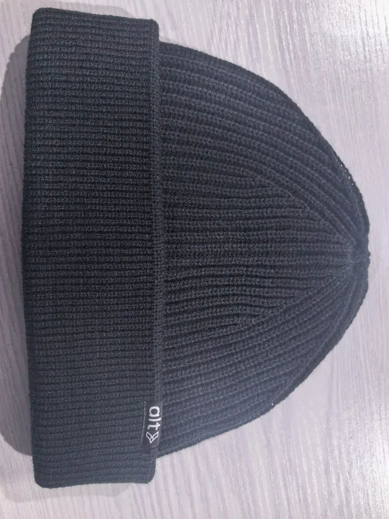 Schwarze Rippstrickmütze mit gefaltetem Bündchen auf hellem Untergrund – gleichmäßige Stricktextur und klar definierter Krempenfalz sichtbar
