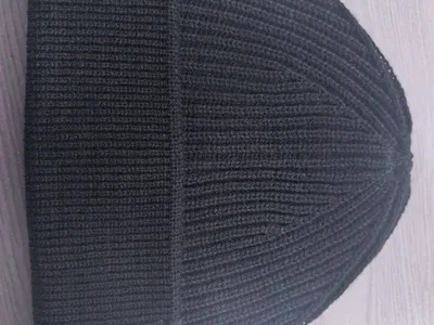 Schwarze Rippstrickmütze mit gefaltetem Bündchen auf hellem Untergrund – gleichmäßige Stricktextur und klar definierter Krempenfalz sichtbar