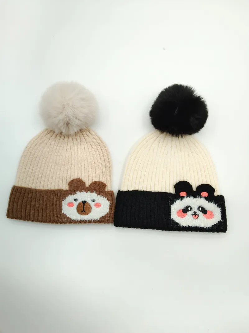 Zwei Rippenstrick-Beanies mit Bommeln: Bärenmotiv auf braunem Kontrastbündchen und Panda-Design auf schwarzem Kontrastbündchen, Draufsicht