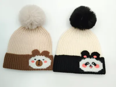 Zwei Strickmützen mit Bommeln: hellbraune Bärenmütze mit Cartoon-Bärengesicht und schwarz-cremefarbene Pandamütze mit Panda-Applikation