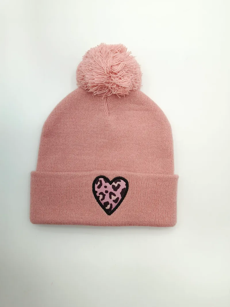 Altrosa Strickbeanie mit weichem Bommel auf der Spitze und auffälligem Herz-Patch im Leopardenmuster am gefalteten Bündchen