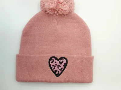 Altrosa Strickbeanie mit weichem Bommel auf der Spitze und auffälligem Herz-Patch im Leopardenmuster am gefalteten Bündchen