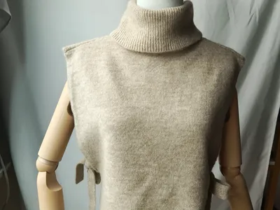 Cremefarbene ärmellose Rollkragen-Strickweste mit seitlichen Bindebändern auf einer Schneiderpuppe