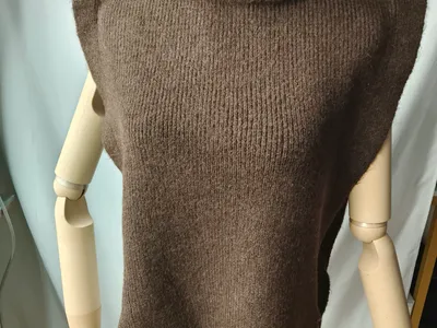 Braune grobgestrickte ärmellose Rollkragen-Weste mit Bogensaum und seitlichem Bindegürtel auf einer Schaufensterpuppe
