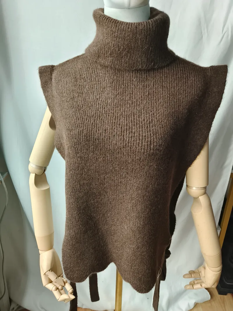 Braune grobgestrickte ärmellose Rollkragen-Weste mit Bogensaum und seitlichem Bindegürtel auf einer Schaufensterpuppe