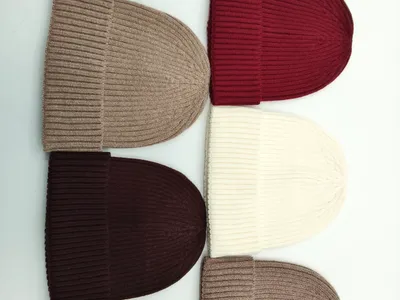 Fünf Rippstrick-Beanies nebeneinander in den Farben Beige, Bordeaux, Creme, Dunkelbraun und Taupe auf weißem Hintergrund