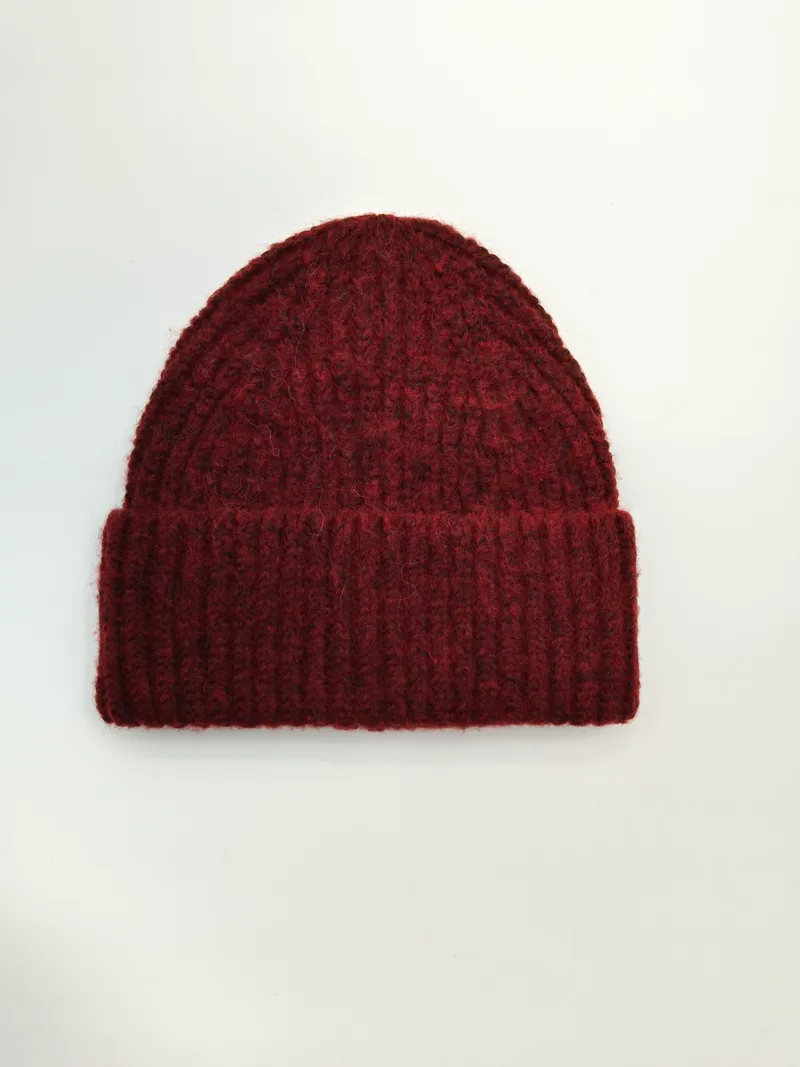 Dunkelrote grobgestrickte Rippstrick-Beanie mit umgeschlagenem Bündchen, flach auf weißem Hintergrund