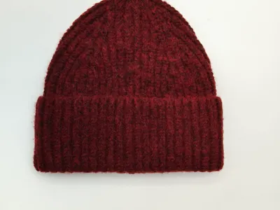 Dunkelrote grobgestrickte Rippstrick-Beanie mit umgeschlagenem Bündchen, flach auf weißem Hintergrund