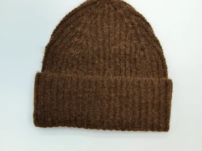 Braune grobgestrickte Winter-Beanie mit Umschlagbündchen, flach auf weißem Untergrund liegend